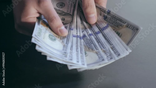 The man picks up a stack of banknotes