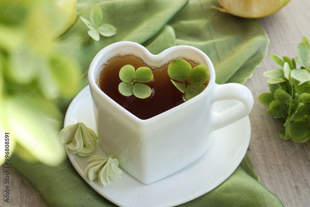 Heart-shaped cup of tea among hydrangea flowers, top view Heart-shaped cup of tea among hydrangea flowers, top view
