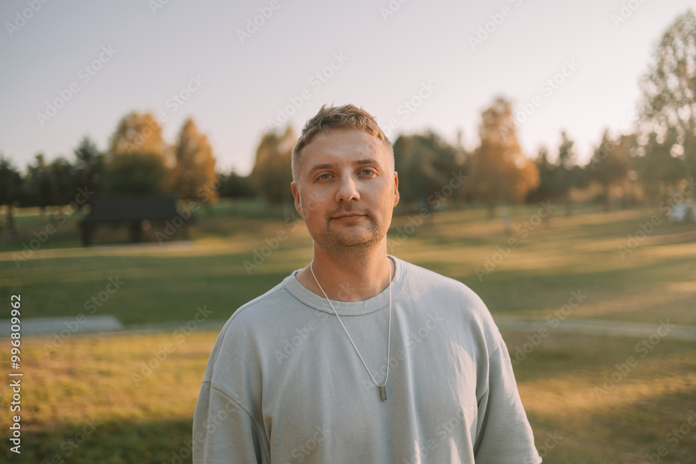 Portrait of happy Caucasian blonde man looking at camera outdoor, walking rest relax in spring green city park go down alley sunshine lawn outdoors on nature. Urban lifestyle leisure concept. High Portrait of happy Caucasian blonde man looking at camera outdoor, walking rest relax in spring green city park go down alley sunshine lawn outdoors on nature. Urban lifestyle leisure concept. High