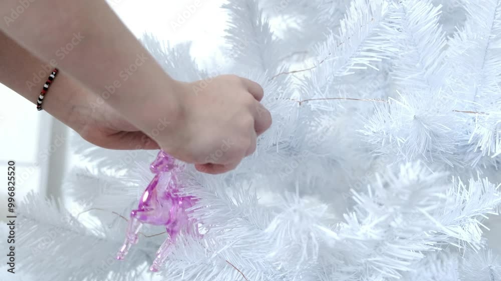 Hands of a girl decorating a white Christmas tree. Hands of a girl decorating a white Christmas tree.