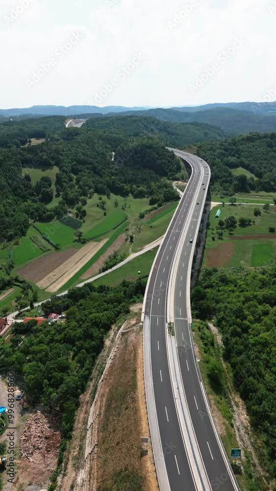 drone view of the road traffic. Highway and rural roads between mountain hills, dense forest and small settlements drone view of the road traffic. Highway and rural roads between mountain hills, dense forest and small settlements