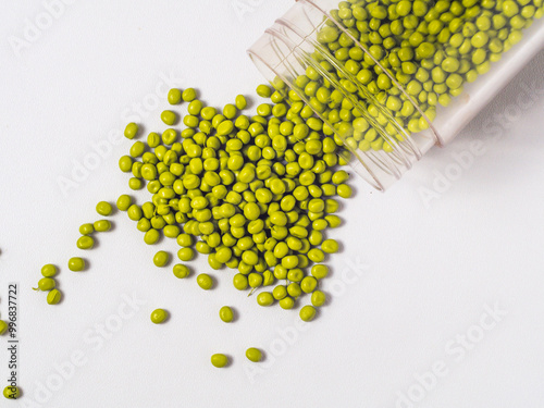 Guacamole masterbatch granules spilling from glass jar on white background photo