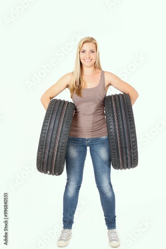 A woman is confidently holding two tires firmly in her hands