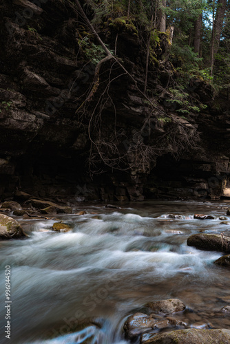 A rugged riverbed is shaped by the force of the stream flowing rapidly over and around the rocks. The dynamic motion of the water energizes the otherwise still landscape. photo