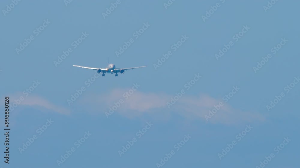 Airliner approaching landing, front view. Jet airliner with unrecognizable livery descending, arriving. Wide-body aircraft in the blue sky Airliner approaching landing, front view. Jet airliner with unrecognizable livery descending, arriving. Wide-body aircraft in the blue sky