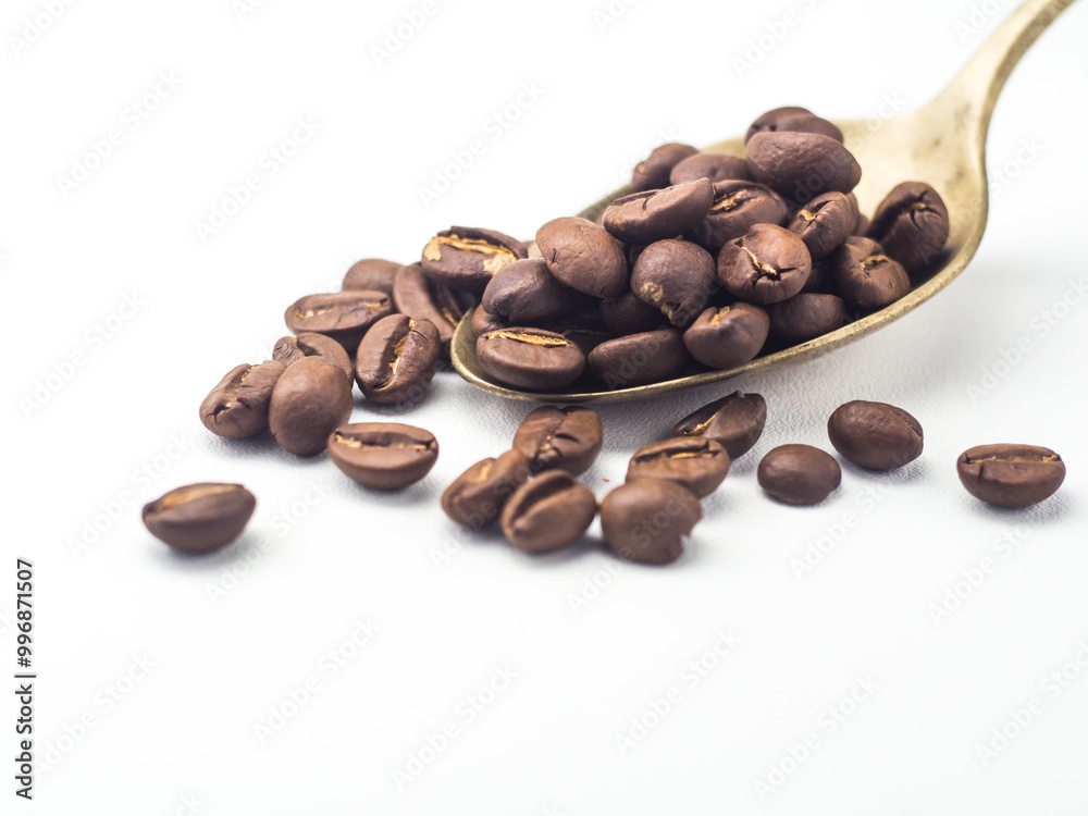 Fototapeta premium Roasted coffee beans with ancient copper spoon on white background
