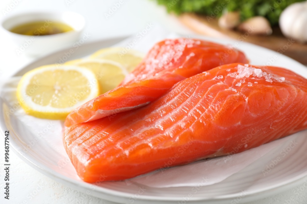 Pieces of fresh salmon with salt and lemon on white table, closeup Pieces of fresh salmon with salt and lemon on white table, closeup