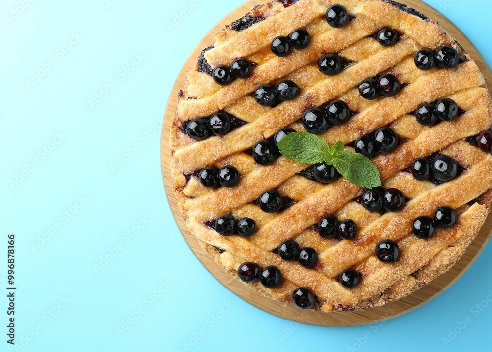 Delicious homemade blueberry pie with mint on light blue background, top view. Space for text Delicious homemade blueberry pie with mint on light blue background, top view. Space for text