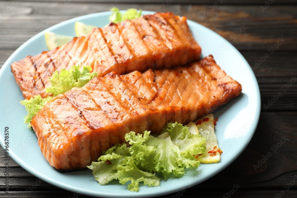 Delicious grilled salmon fillets with lettuce and lemon on wooden table, closeup Delicious grilled salmon fillets with lettuce and lemon on wooden table, closeup