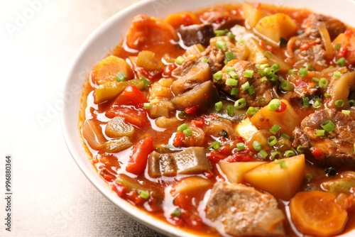 Delicious stew with vegetables in bowl on light grey table, closeup