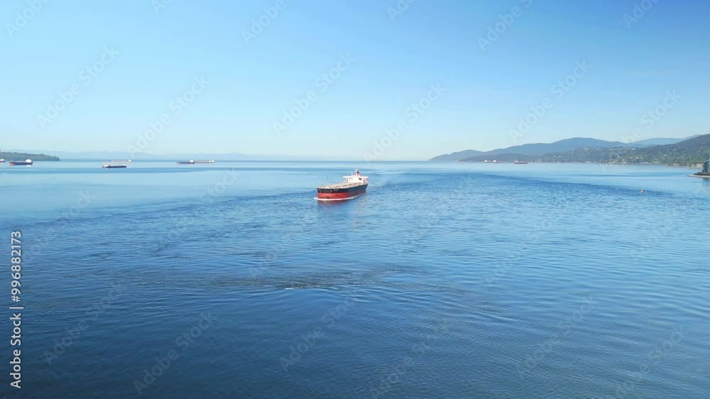 Cargo ship crossing under the bridge near Vancouver bay with city skyline in the distance