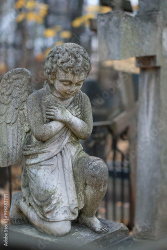 angel baby statue on old cemetery, autumn nature background. Design for condolences, mourning card or obituary. symbol of religion, faith, Remember, mourn, memory. all saints day, All Souls Day