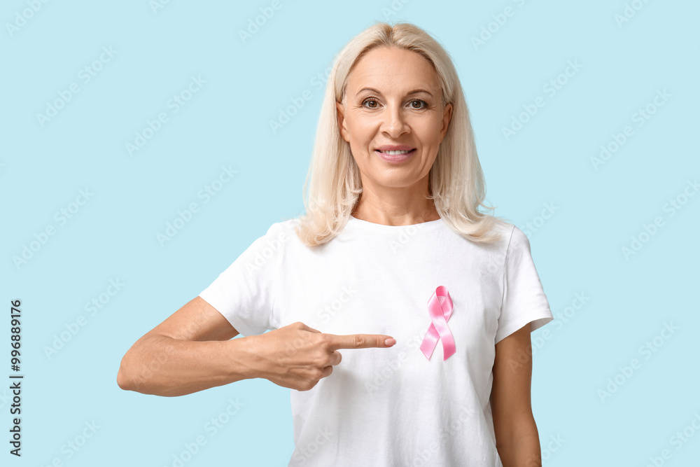 Mature woman with pink ribbon on blue background. Breast cancer awareness concept Mature woman with pink ribbon on blue background. Breast cancer awareness concept