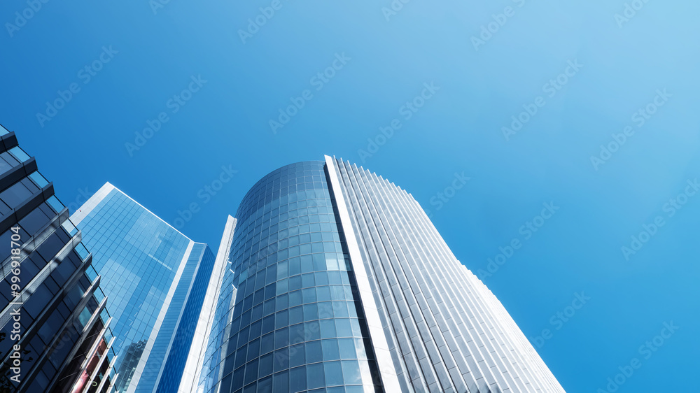 Modern skyscrapers reaching towards a clear blue sky in a urban setting, business background Modern skyscrapers reaching towards a clear blue sky in a urban setting, business background