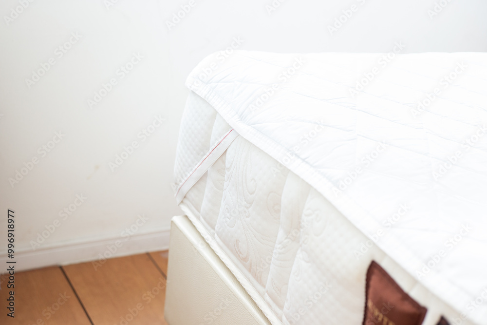 Bed with mattress in the bedroom. Protective waterproof cover on the mattress. Using a mattress pad Bed with mattress in the bedroom. Protective waterproof cover on the mattress. Using a mattress pad