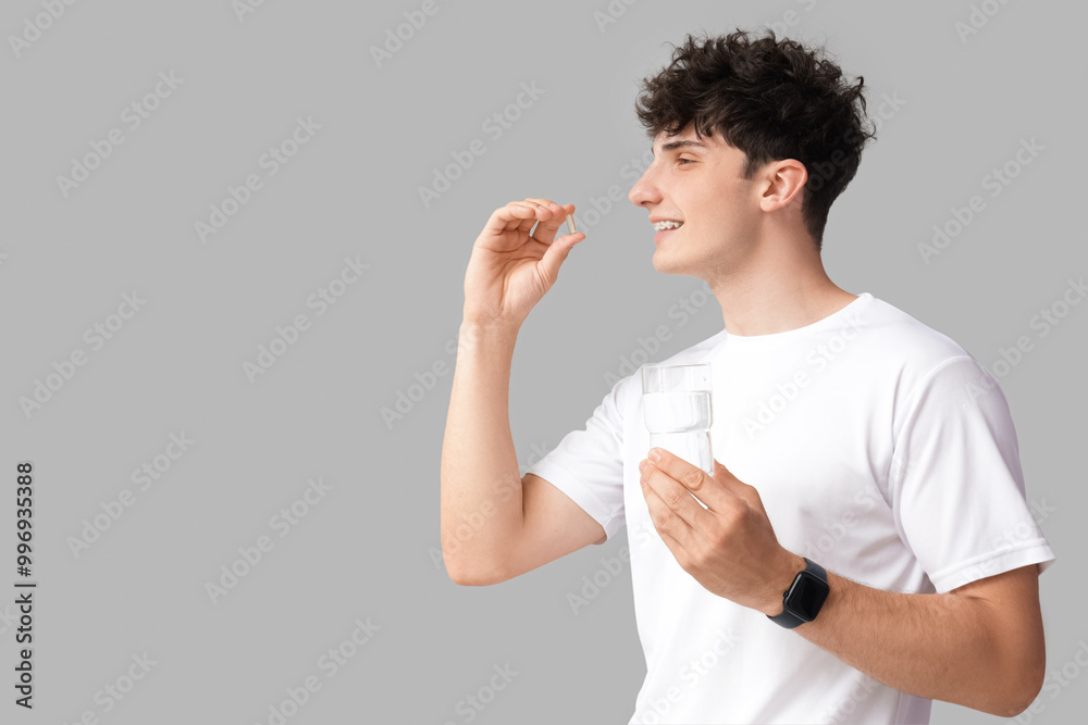 Young man taking fish oil on grey background Young man taking fish oil on grey background