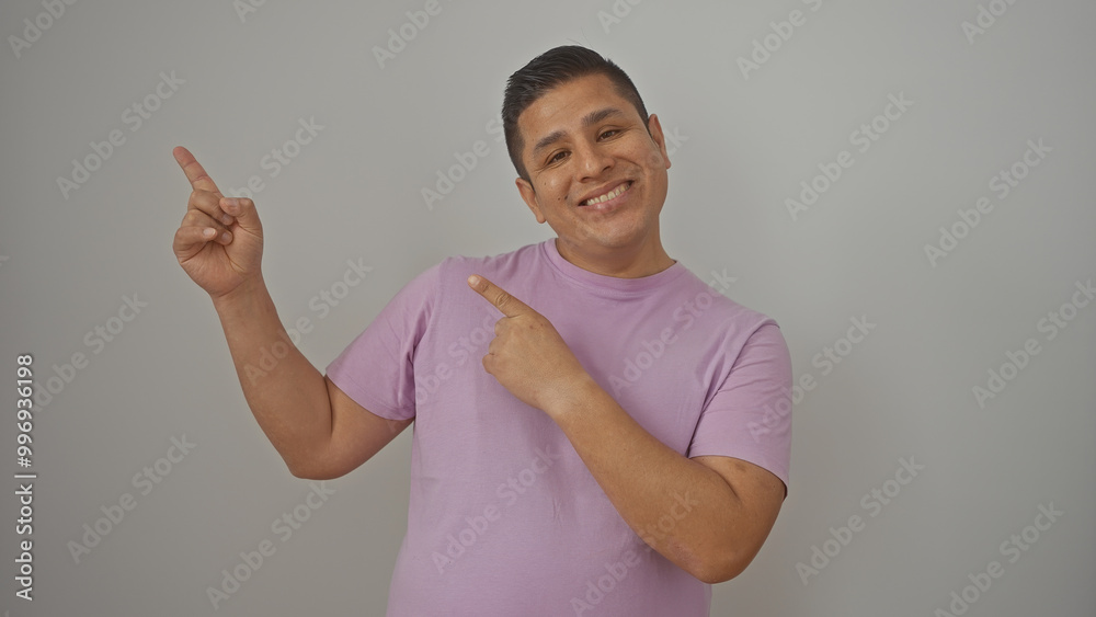 A smiling young hispanic man in a purple shirt pointing up against a white background A smiling young hispanic man in a purple shirt pointing up against a white background