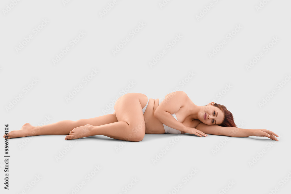 Beautiful plus size woman in underwear lying on light background Beautiful plus size woman in underwear lying on light background