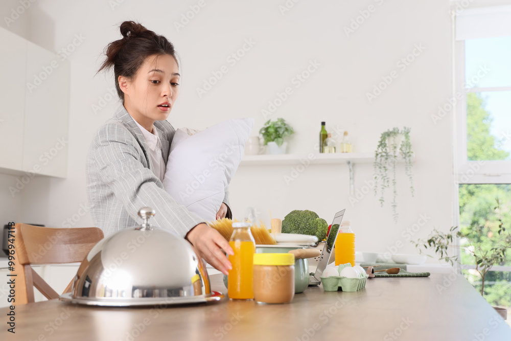 Overwhelmed Asian mother in suit with baby and cooking while working at home. Multitasking concept Overwhelmed Asian mother in suit with baby and cooking while working at home. Multitasking concept