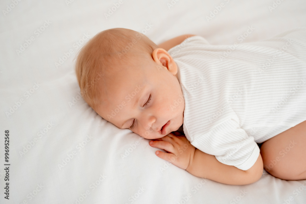 a newborn baby sleeps sweetly on his tummy, a place for text, a baby sleeps on a white bed with a pen under his cheek, a healthy baby's sleep, a close-up portrait a newborn baby sleeps sweetly on his tummy, a place for text, a baby sleeps on a white bed with a pen under his cheek, a healthy baby's sleep, a close-up portrait