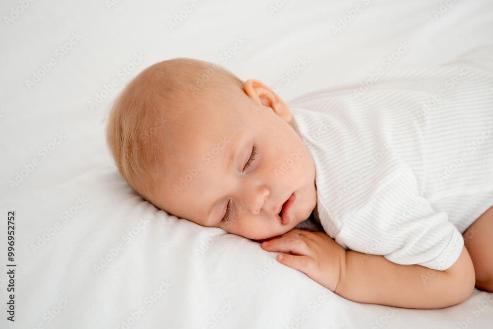 a newborn baby sleeps sweetly on his tummy, a place for text, a baby sleeps on a white bed with a pen under his cheek, a healthy baby's sleep, a close-up portrait a newborn baby sleeps sweetly on his tummy, a place for text, a baby sleeps on a white bed with a pen under his cheek, a healthy baby's sleep, a close-up portrait