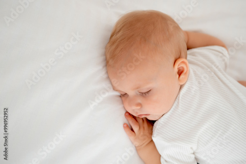 a newborn baby sleeps sweetly on his tummy, a place for text, a baby sleeps on a white bed with a pen under his cheek, a healthy baby's sleep, a close-up portrait