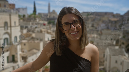 A beautiful young hispanic woman smiling at a historic viewpoint in the old town of matera, basilicata, italy, showcasing the charming european architecture in the background.