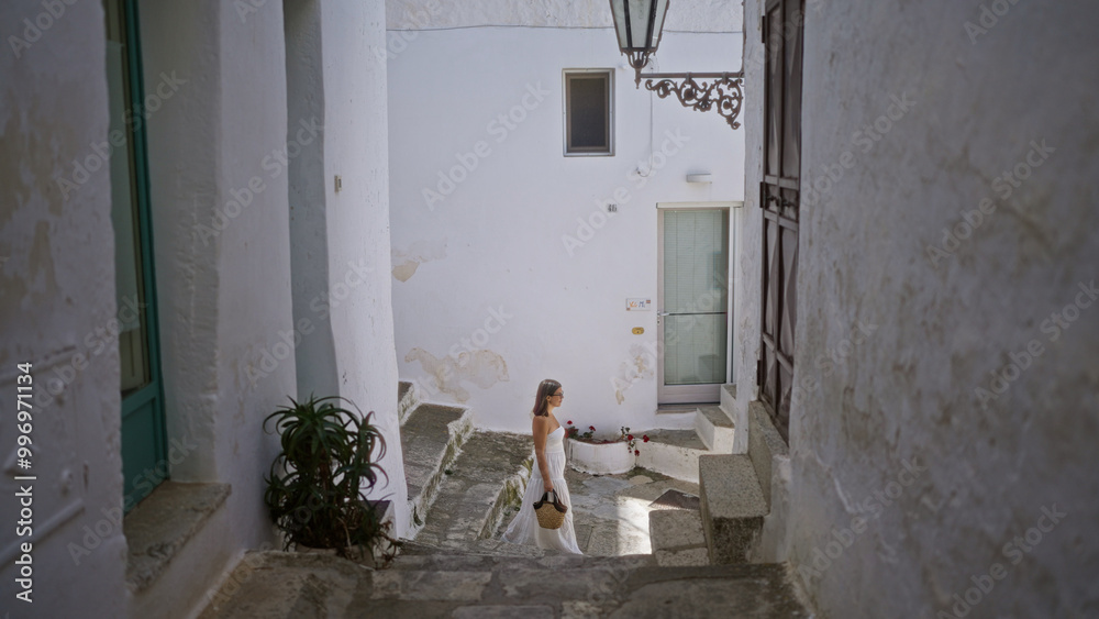 Young hispanic woman walking through the charming old town of ostuni in puglia, italy, on a sunny day. Young hispanic woman walking through the charming old town of ostuni in puglia, italy, on a sunny day.