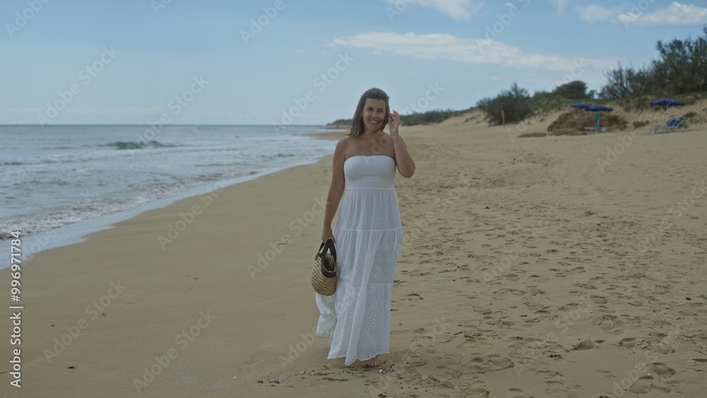 A beautiful young hispanic woman walks along the serene beach of pescoluse in puglia, italy, dressed in a flowing white sundress and carrying a straw bag. A beautiful young hispanic woman walks along the serene beach of pescoluse in puglia, italy, dressed in a flowing white sundress and carrying a straw bag.
