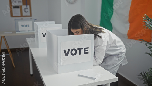 Hispanic woman voting in an irish electoral college room with a flag in the background. photo