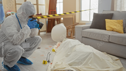 Forensic man photographing evidence in a living room crime scene with a body, glasses, and couch.