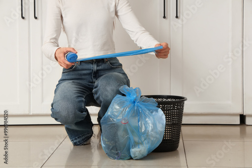 Woman changing garbage bag in trash bin at home