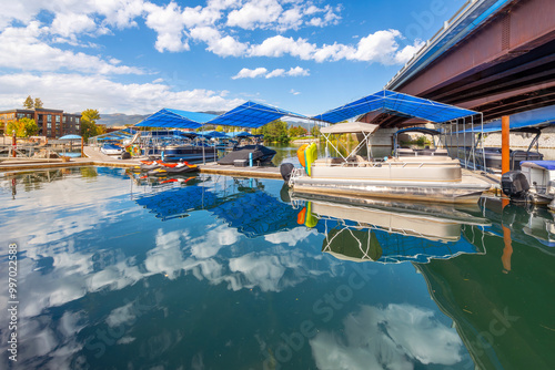 Fototapeta Naklejka Na Ścianę i Meble -  Boats in boat slips docked at the Sandpoint Marina, with the small town main street of Sandpoint Idaho behind, on Lake Pend Oreille in the North Idaho Panhandle region.