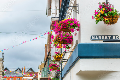 Colorful flower baskets and matching colored flags across Market and High Street in the historic old town of Winchester, England, UK. photo