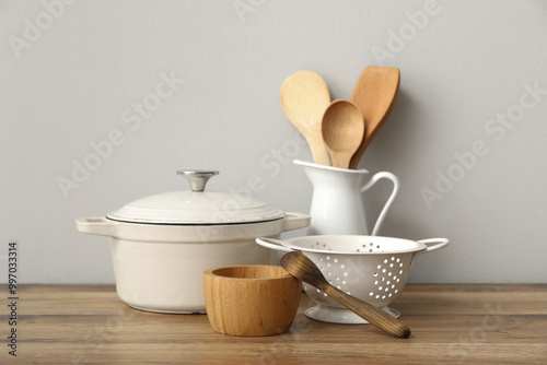 Canvastavla Cooking pot, colander and wooden utensils on table near white wall
