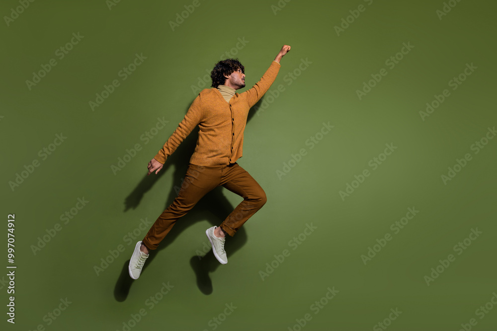 Full length photo of handsome young guy flying superhero dressed stylish brown garment isolated on khaki color background Full length photo of handsome young guy flying superhero dressed stylish brown garment isolated on khaki color background