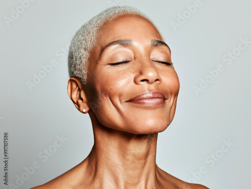 Serene portrait of an older African American woman with short gray hair, smiling with eyes closed, embracing peace and aging gracefully