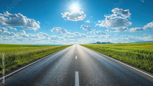 Wide open road leading into the horizon with clear blue sky and white clouds