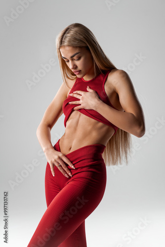 Fitness woman showing abs and flat stomach, isolated. Sporty girl with fit belly photo