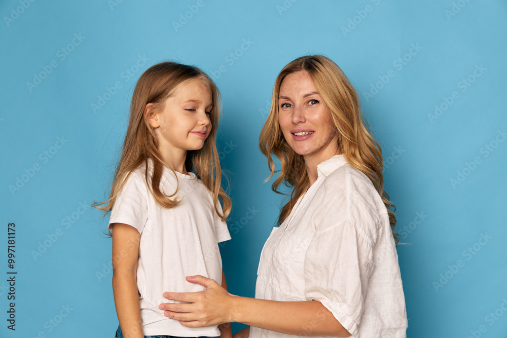 Mother and daughter bonding against a vibrant blue background, showcasing love and togetherness in a bright setting Mother and daughter bonding against a vibrant blue background, showcasing love and togetherness in a bright setting