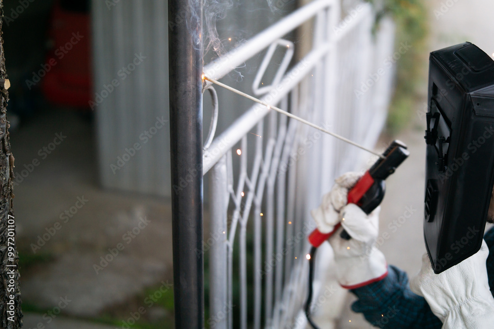 Close up of a welder welding metal fence outdoor Close up of a welder welding metal fence outdoor