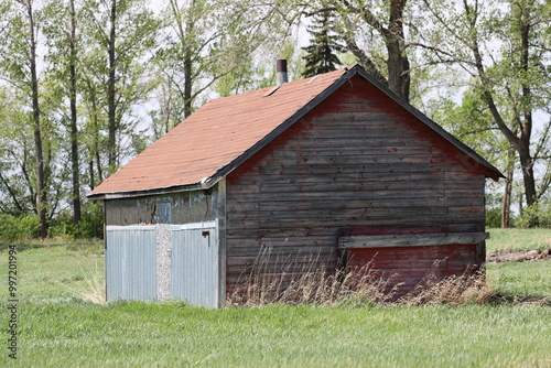 dilapidated abandoned wooden farm building with faded classic red paint