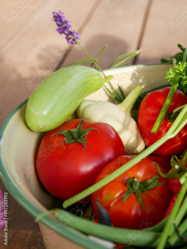 Bowl filled with newly harvested produce. Home grown and organic vegetables. Tomatoes, zucchini, parsley, flowers, apples, pears, beans, peppers, chillies and kale. photo