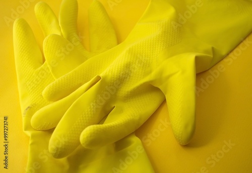 a pair of two yellow gloves for cheaning in an orange background 