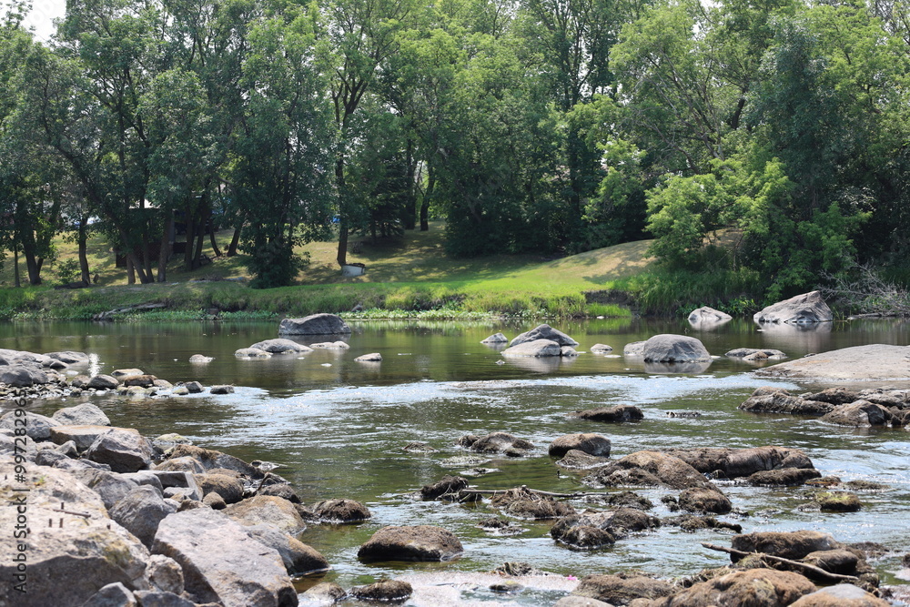 rocks slowing the water in a river in a shady pastoral setting rocks slowing the water in a river in a shady pastoral setting