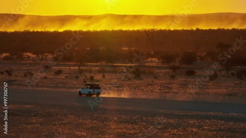 White pick up four by four carrying equipment, driving on the sand of the Namib desert .