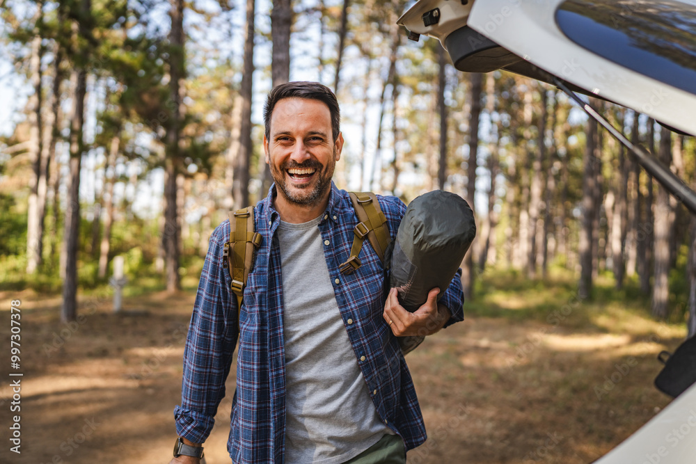 Obraz premium Portrait of adult man hold camping gear near car, ready for camping