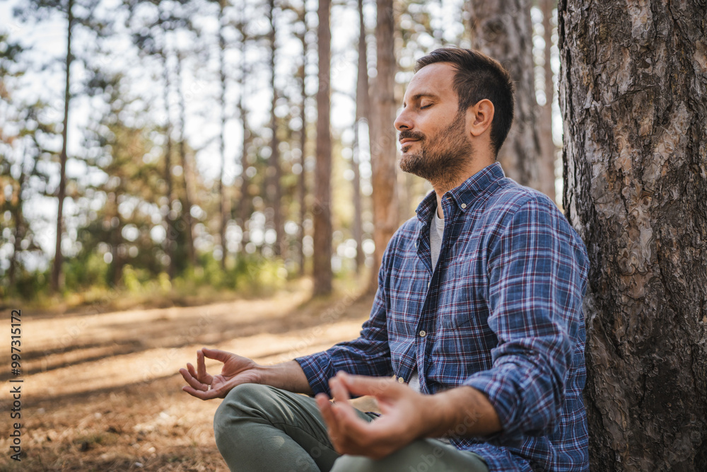 Adult man camper practice meditation and breath exercise in front tree Adult man camper practice meditation and breath exercise in front tree