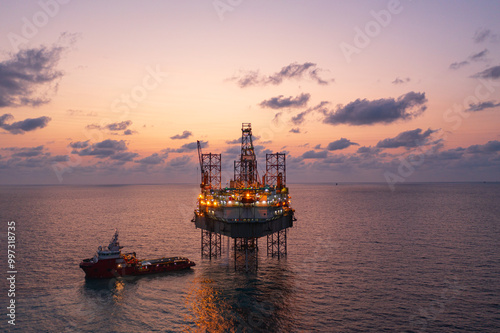 Aerial view of silhouette offshore jack up drilling rig during sunset - oil and gas industry.