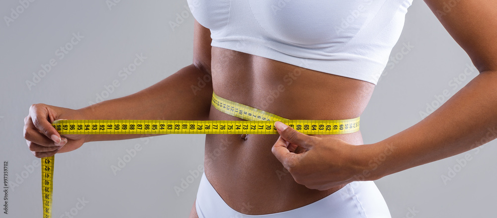 Φωτογραφία Close up of young african woman measuring her waist over grey background, well f